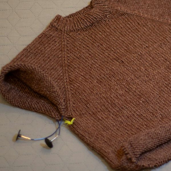 A rust-colored knit sweater laid flat